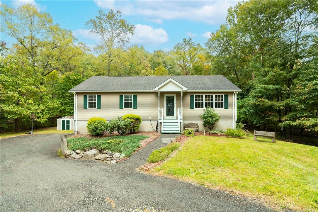 View of front of home featuring a storage unit, a front lawn, and a garage