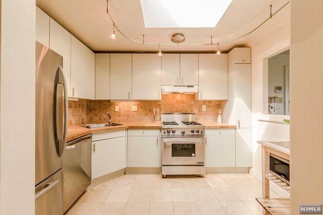 a kitchen with stainless steel appliances granite countertop a refrigerator sink stove and white cabinets