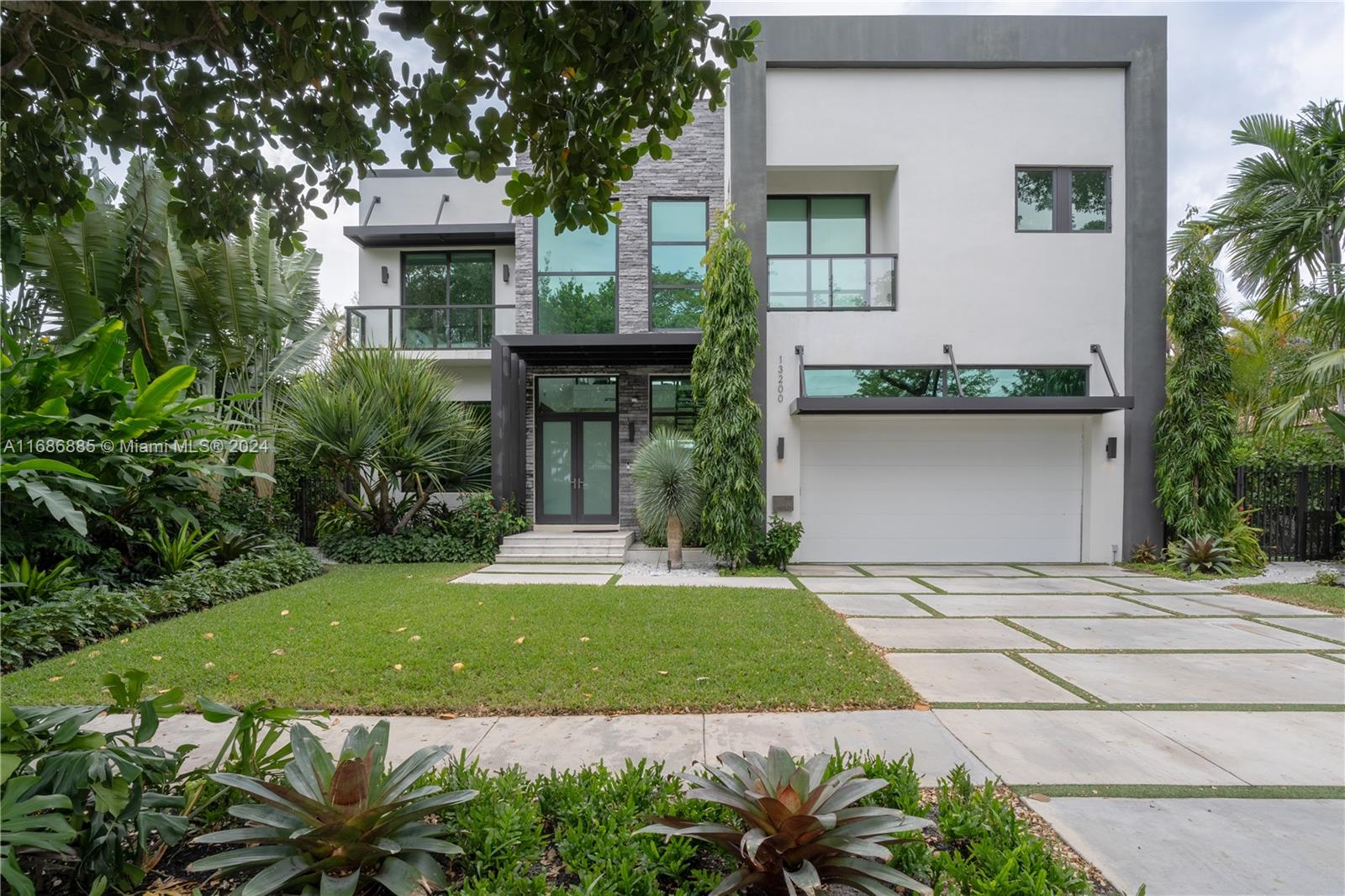 a front view of a house with a yard and potted plants