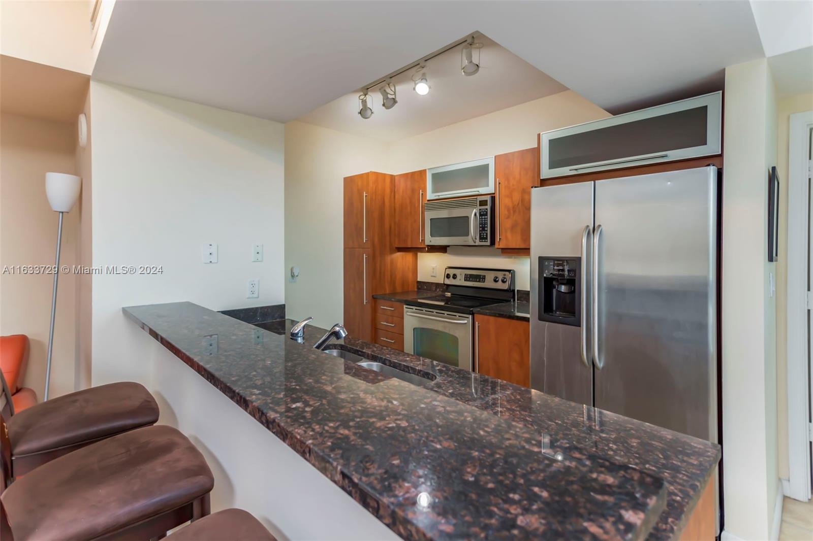 a kitchen with stainless steel appliances granite countertop a refrigerator and a stove top oven