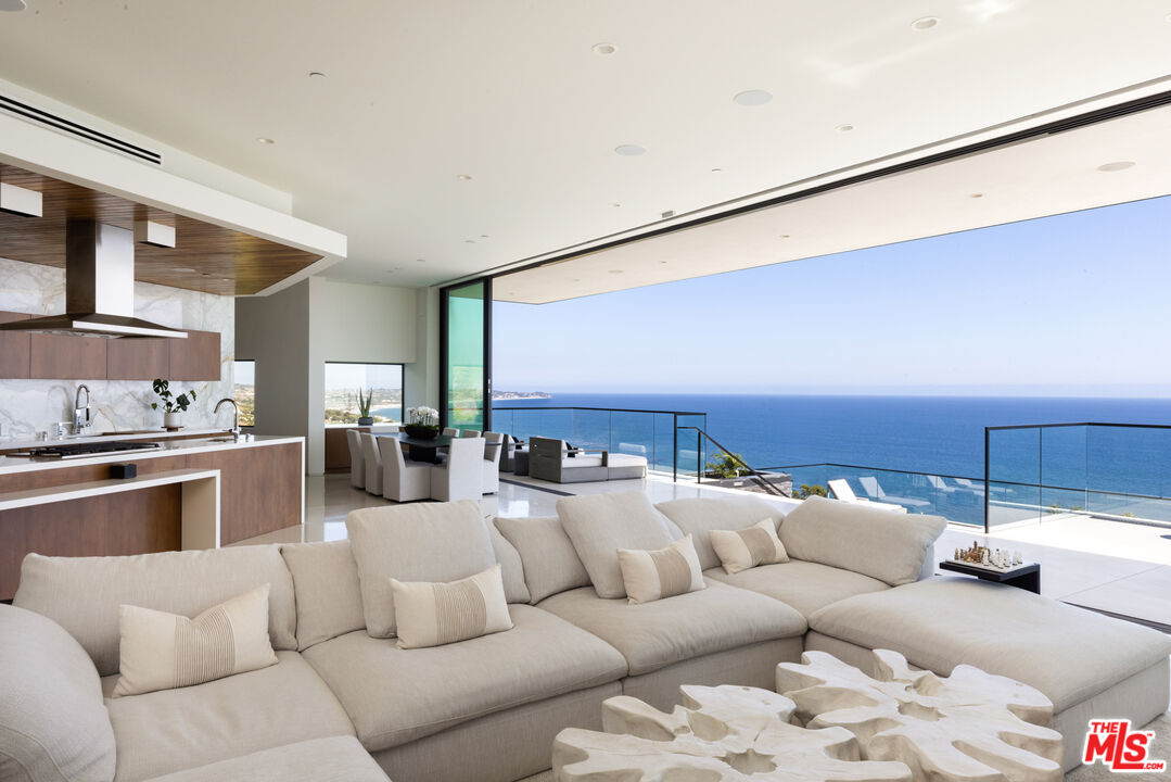 a living room with furniture kitchen view and a large window