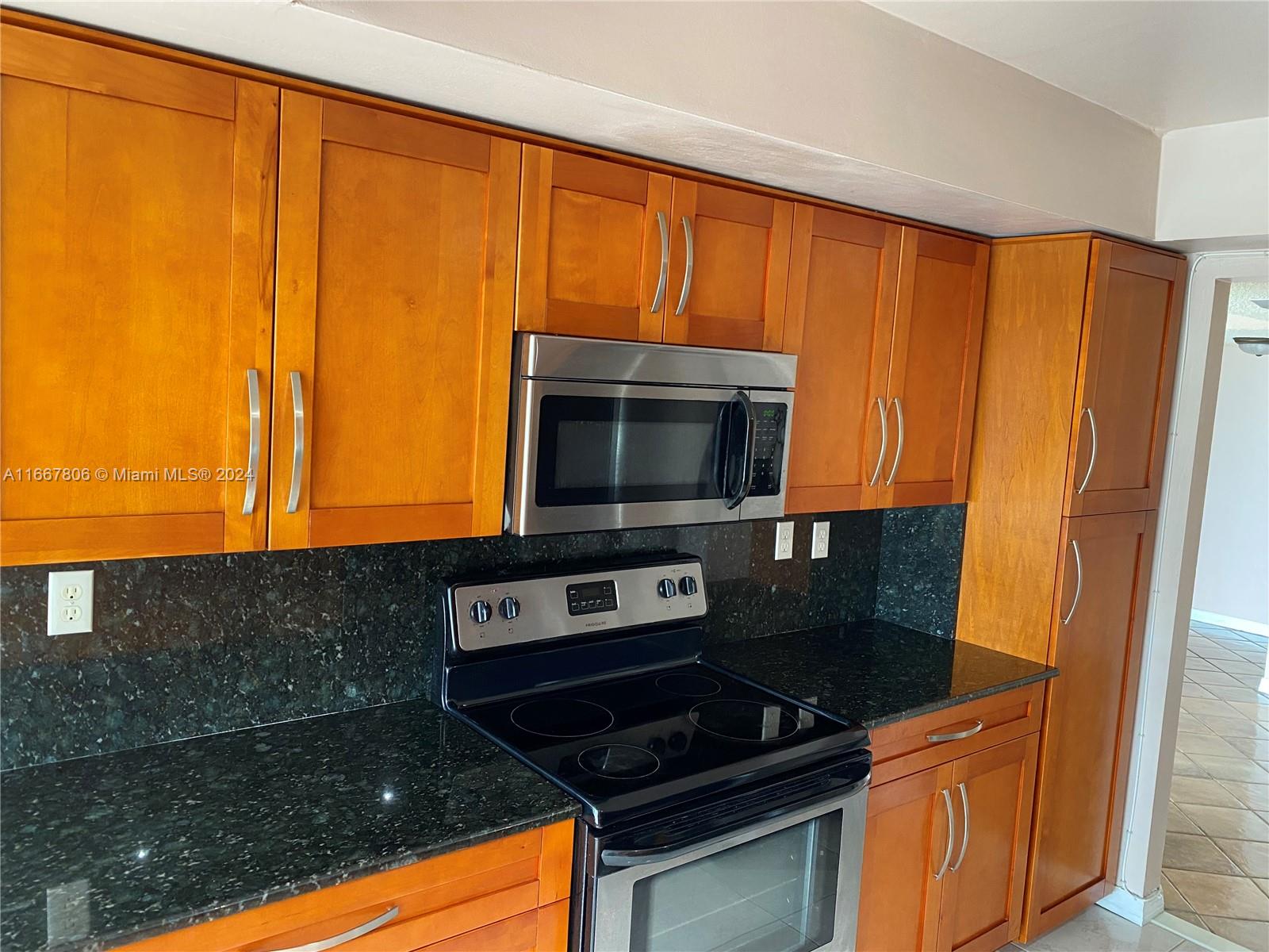 a kitchen with stainless steel appliances granite countertop a stove top oven microwave and cabinets