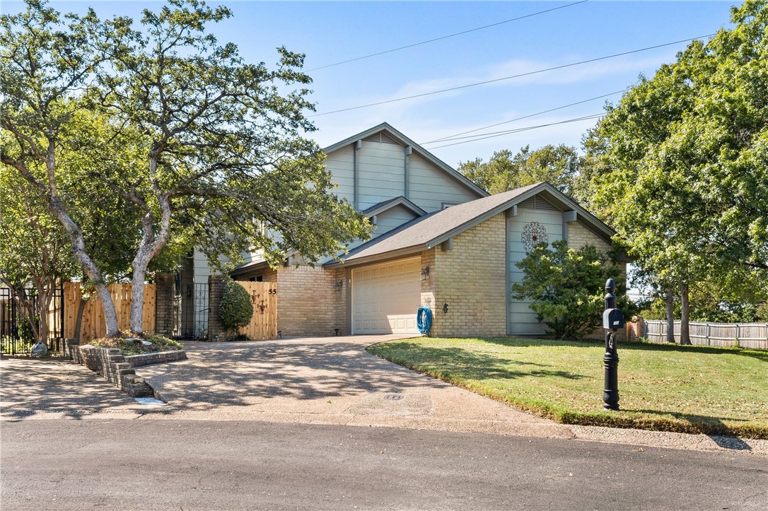 a view of a house with a yard and large tree