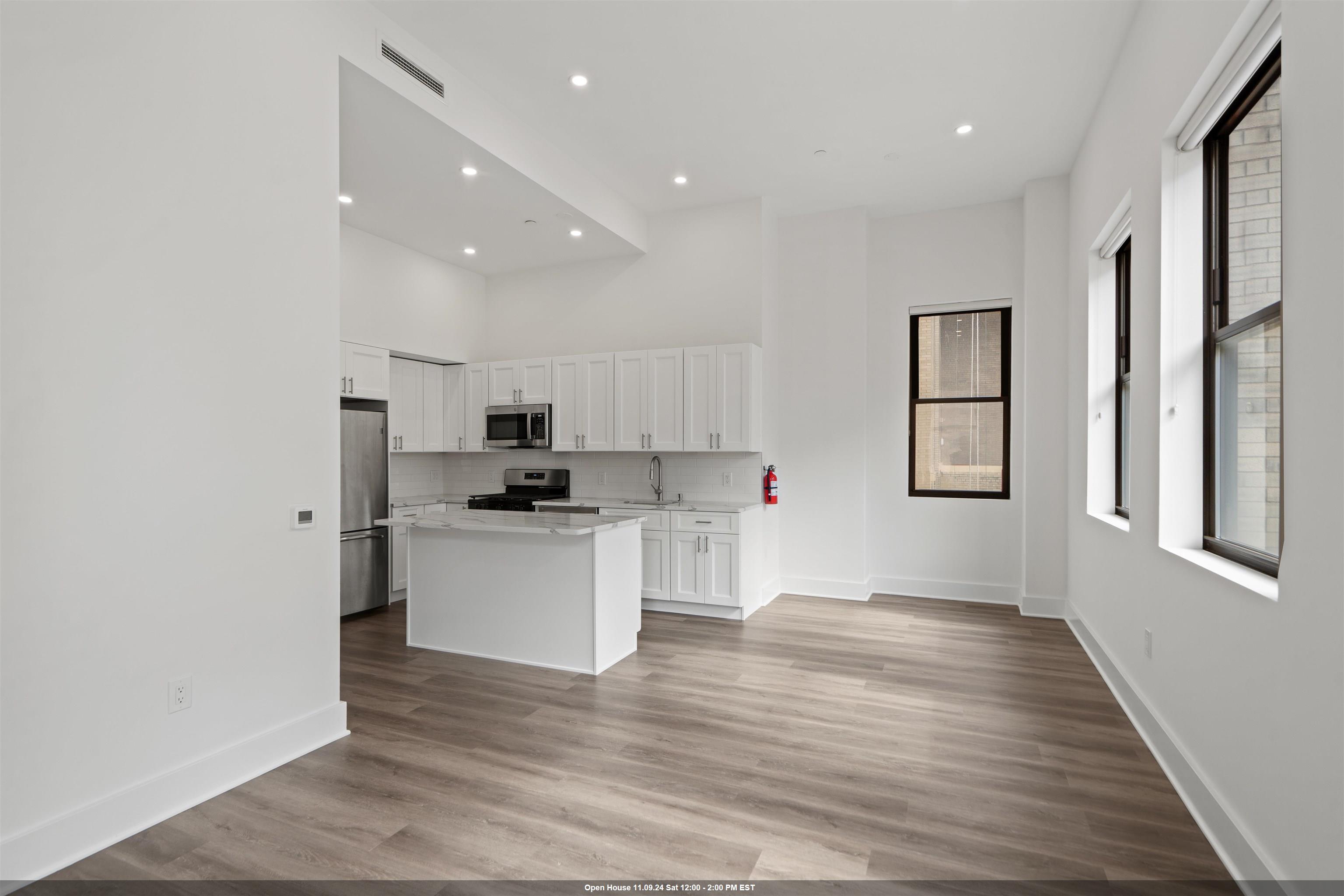 a kitchen with stainless steel appliances granite countertop a refrigerator sink and white cabinets