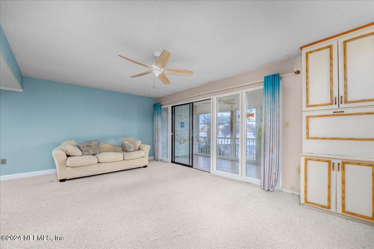 a living room with furniture a ceiling fan and a large window