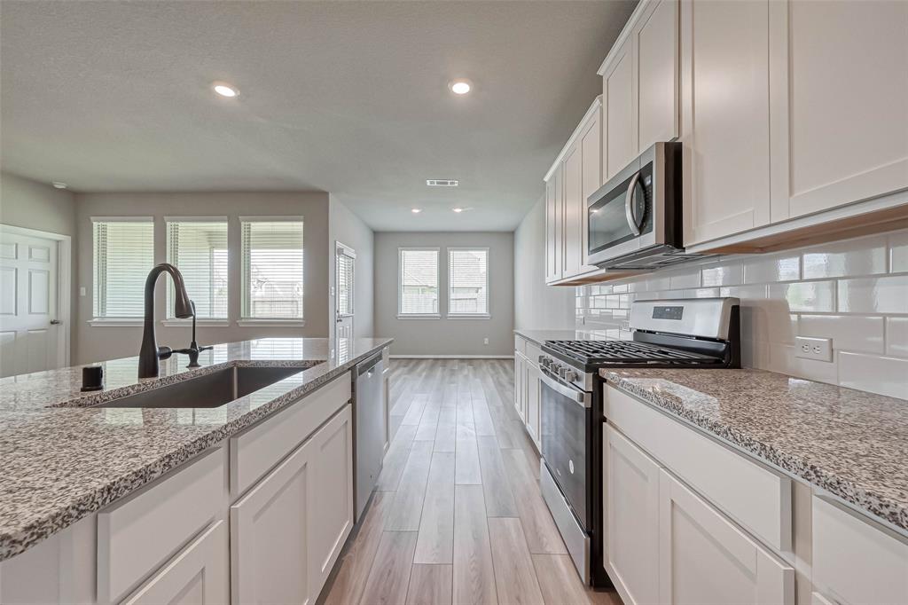 a kitchen with stainless steel appliances granite countertop a sink a stove and a wooden floors