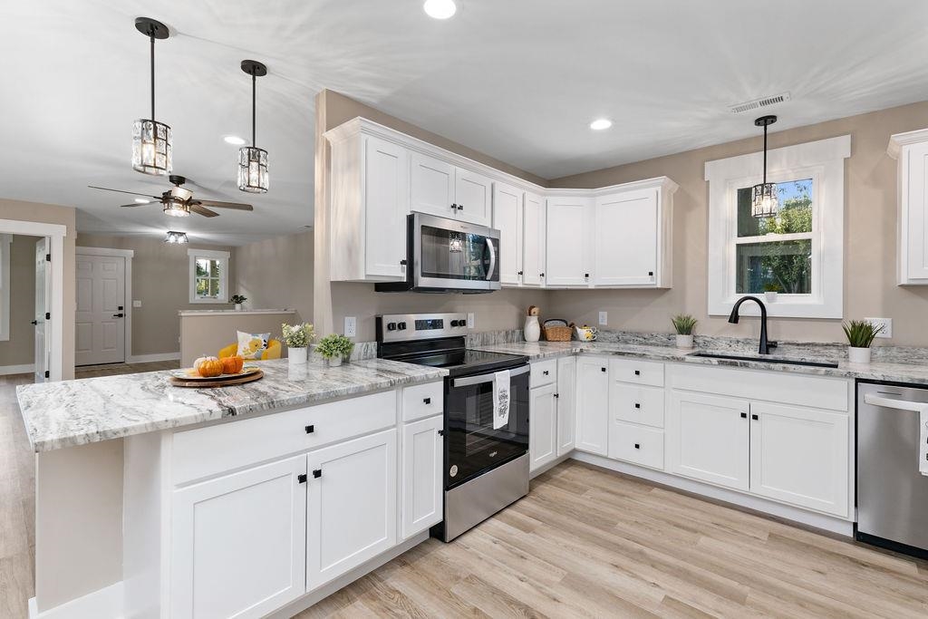 a kitchen with stainless steel appliances granite countertop a sink a stove a refrigerator and cabinets