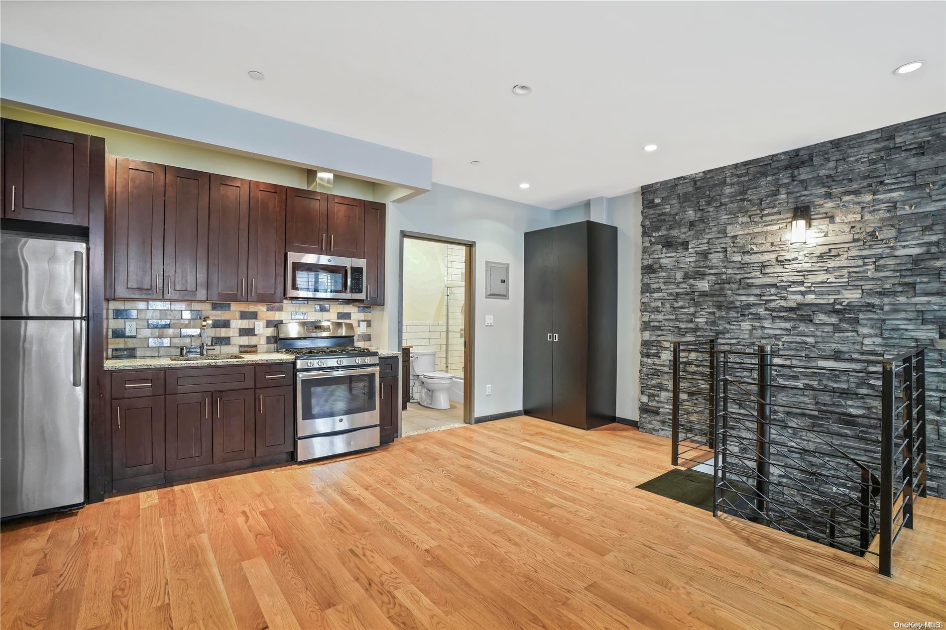 a kitchen with stainless steel appliances kitchen island granite countertop a refrigerator and a stove top oven