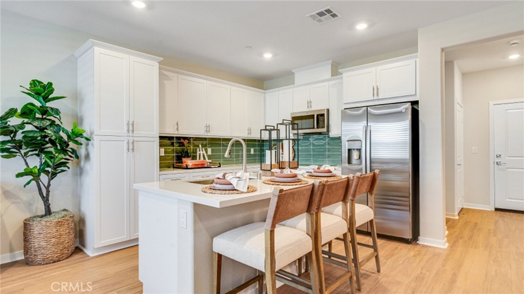 a kitchen with stainless steel appliances a dining table chairs and a refrigerator