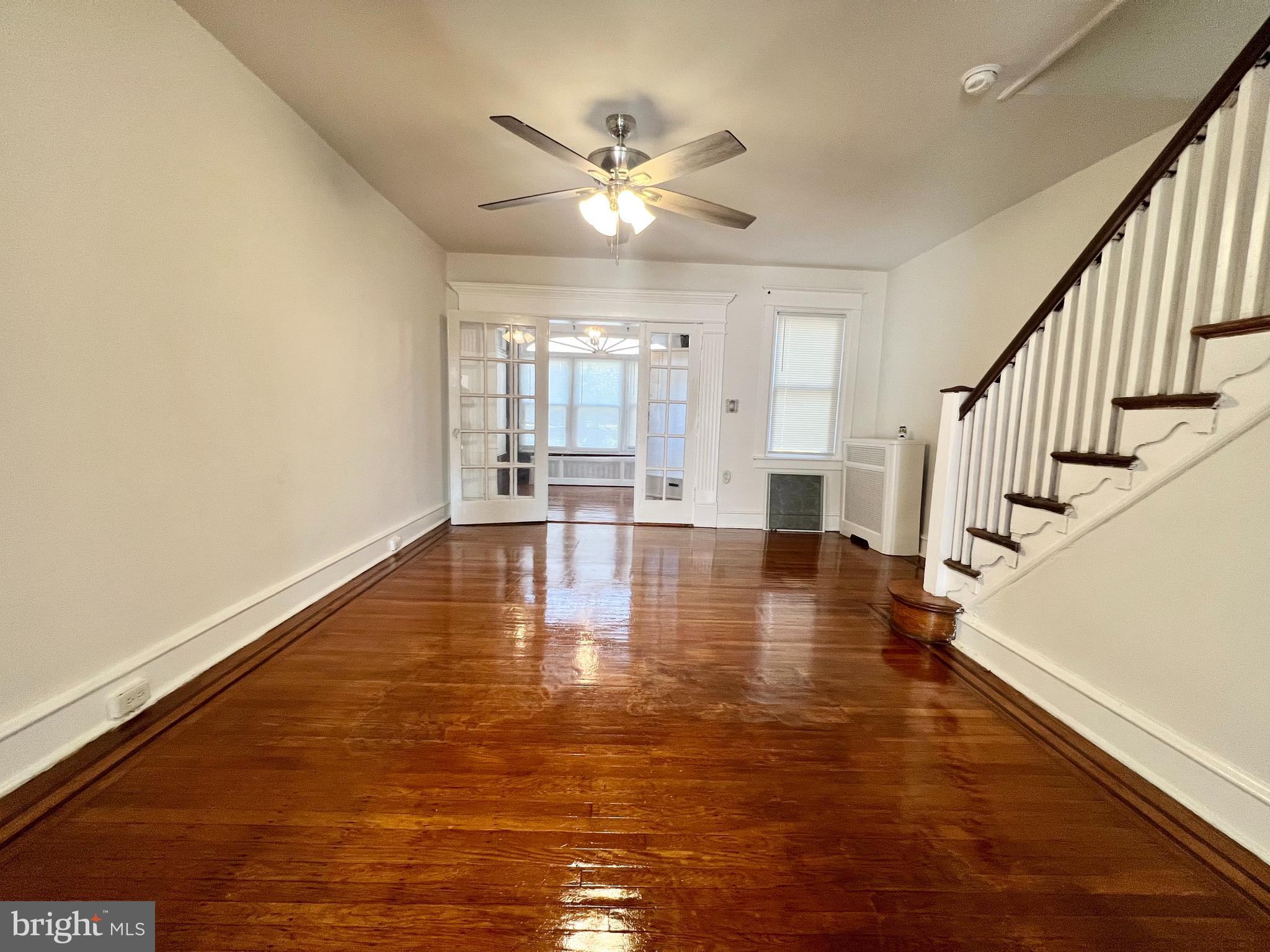 a view of empty room with wooden floor and fan