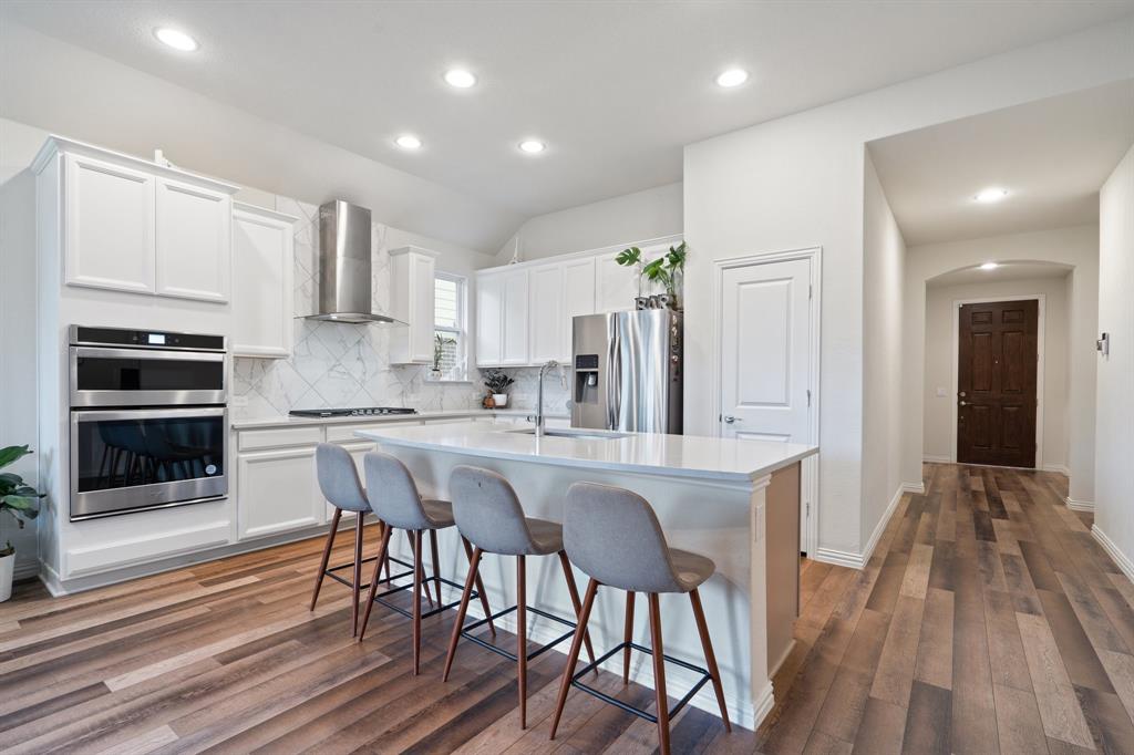 a kitchen with stainless steel appliances a dining table chairs and wooden floor