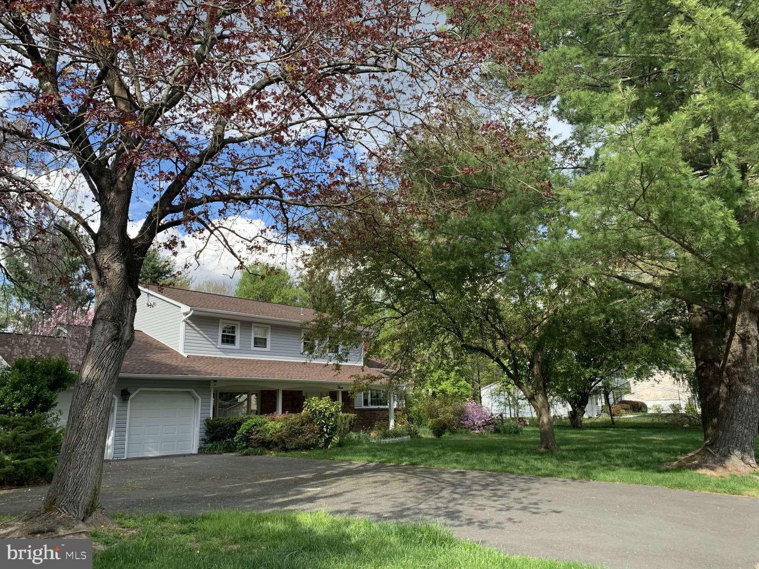 a view of house in front of a big yard with large trees