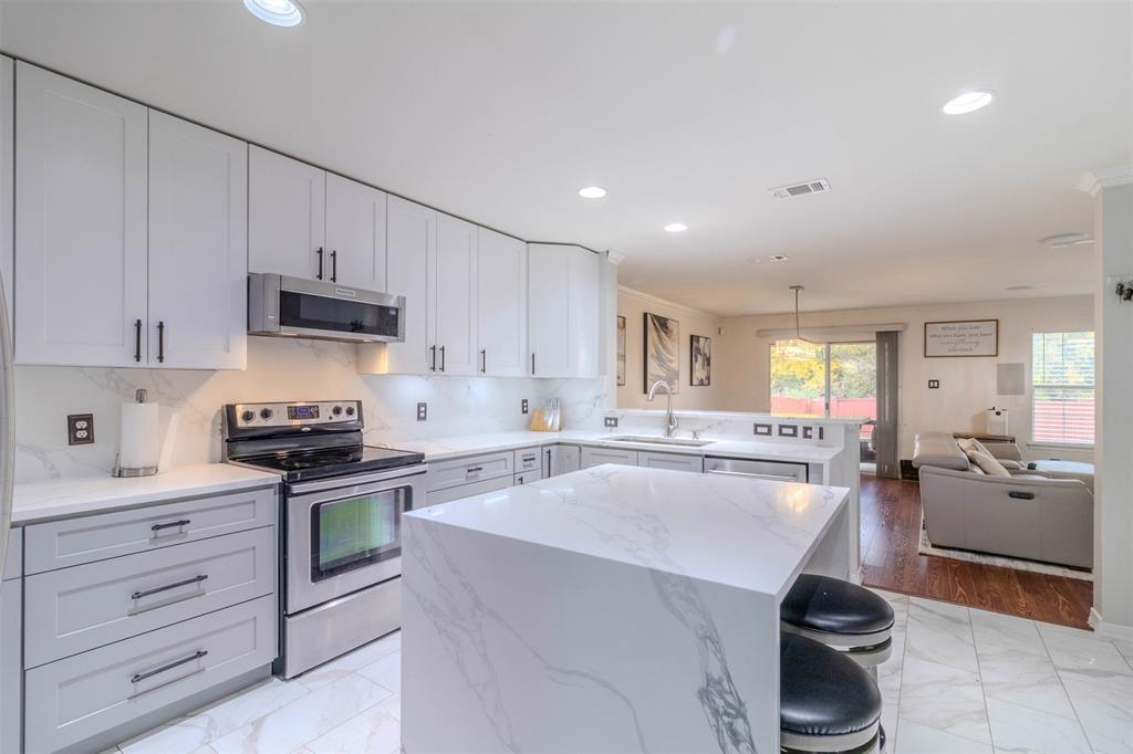 a kitchen with kitchen island granite countertop a sink a stove and cabinets