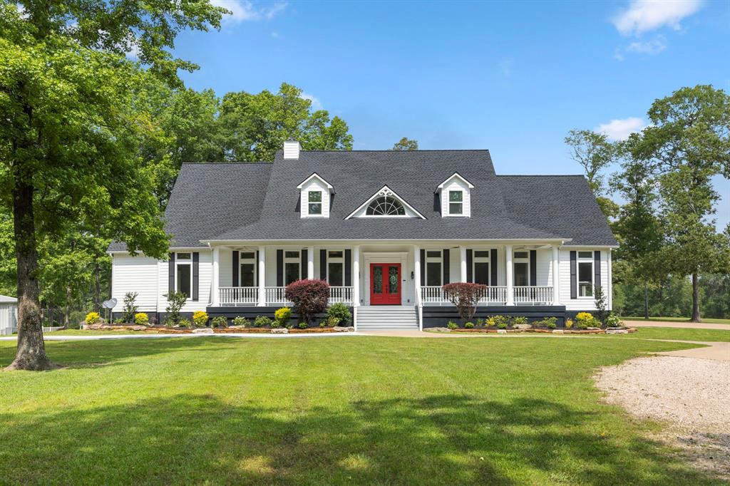 a front view of a house with garden and trees