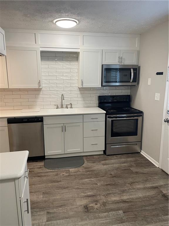 a kitchen with stainless steel appliances white cabinets a sink and a stove