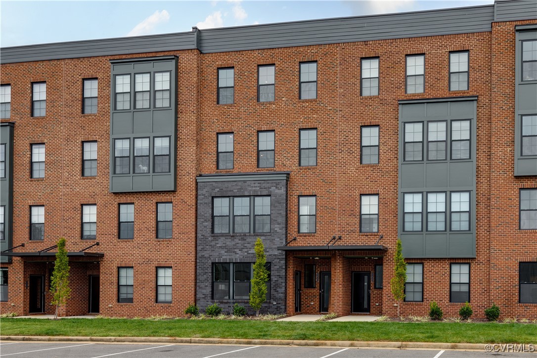 a front view of a brick building with many windows and yard