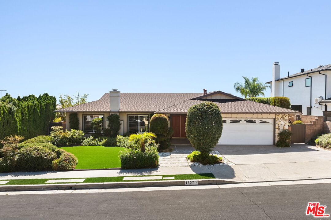 a front view of a house with a yard and potted plants