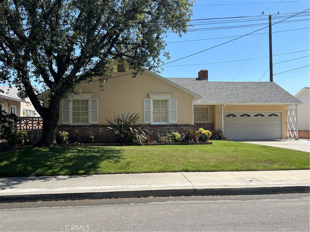 a front view of a house with a garden and trees