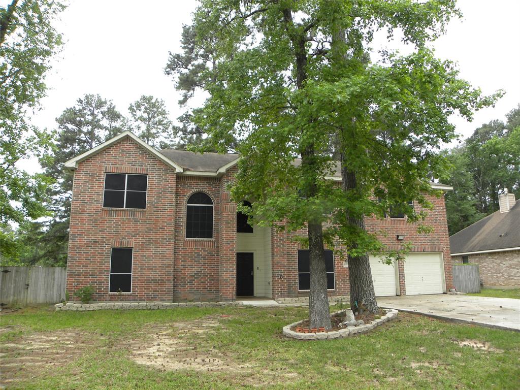 a front view of a house with a yard and large tree