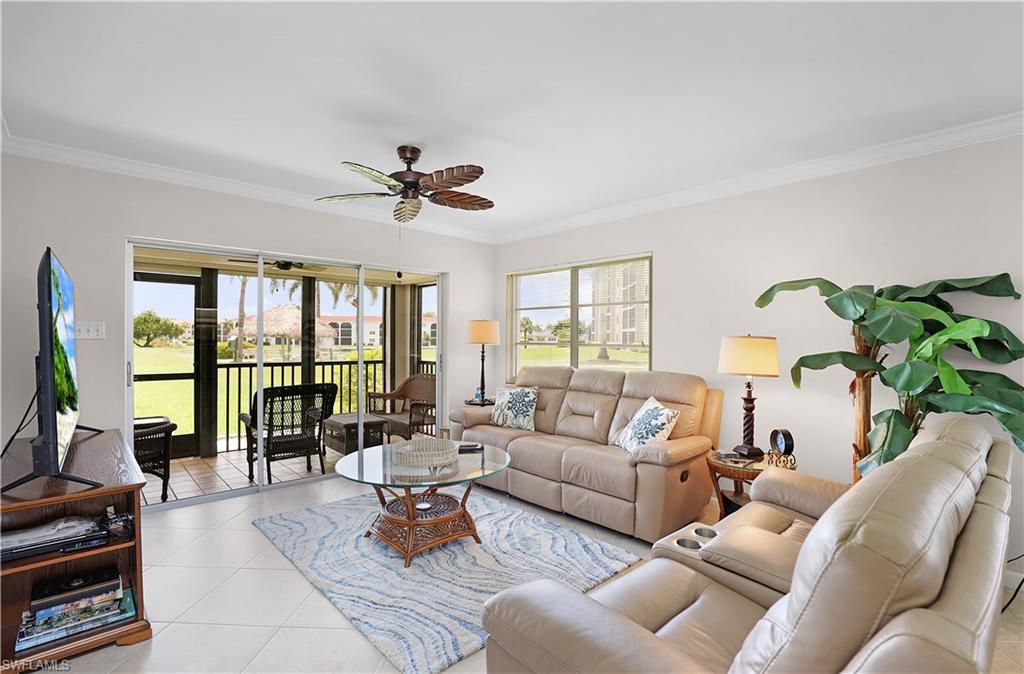 Living room featuring light tile patterned flooring, ornamental molding, and ceiling fan