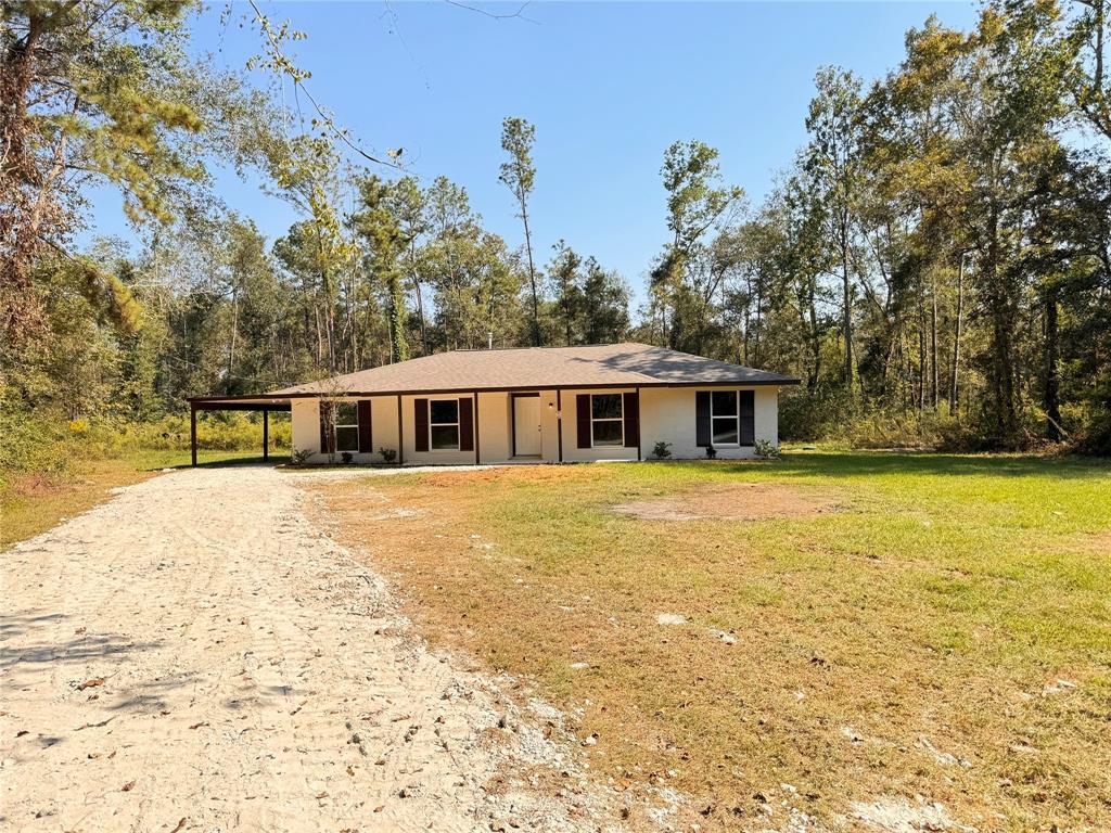 a front view of house with yard and trees in the background