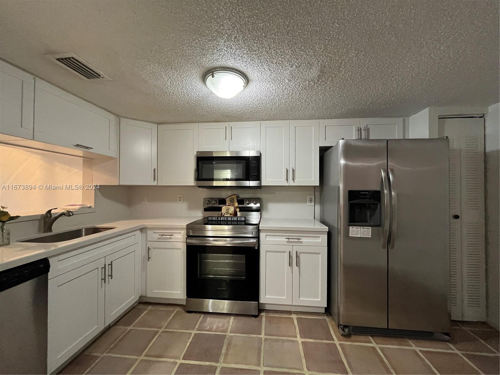 a kitchen with stainless steel appliances a refrigerator sink and microwave