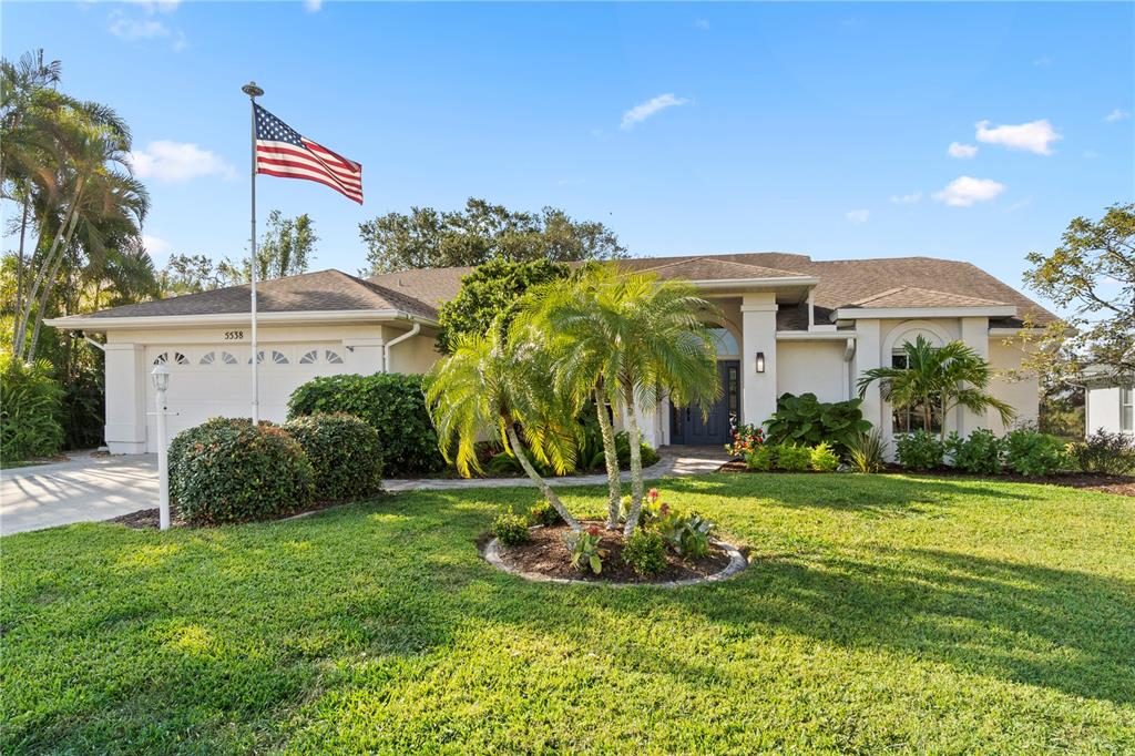 a front view of a house with a yard and palm trees