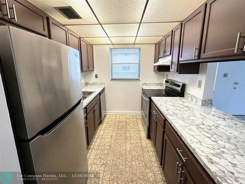 a kitchen with granite countertop a refrigerator and stove