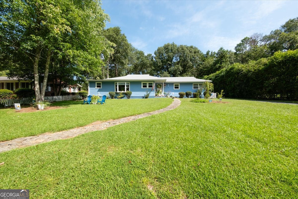 a view of a house with a big yard potted plants and large tree