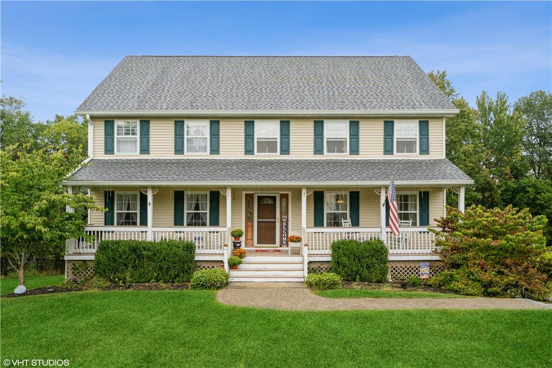 View of front facade featuring a front yard and covered porch