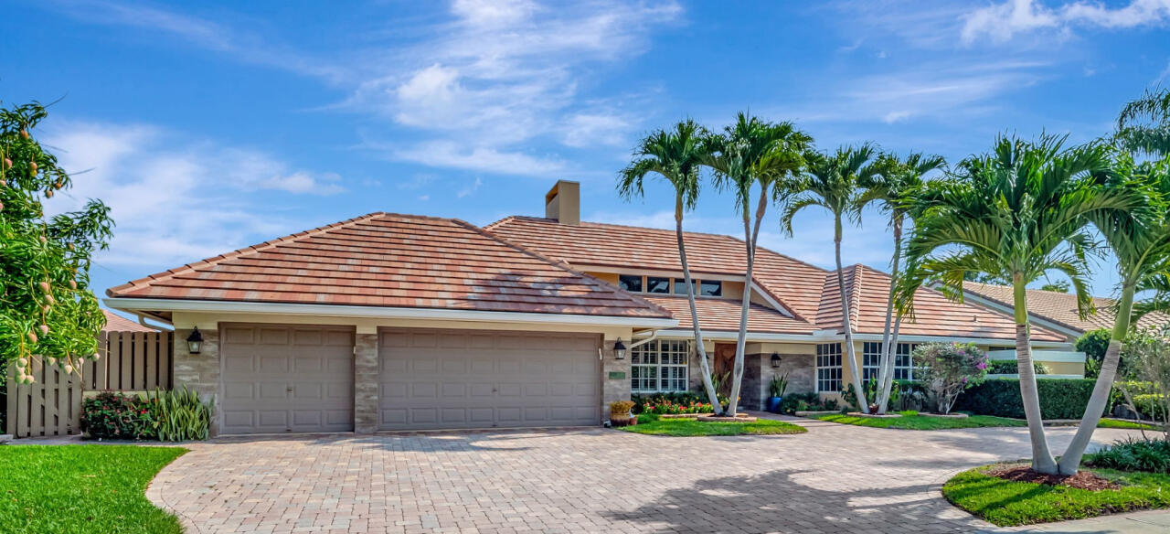 a front view of a house with a garden and palm trees