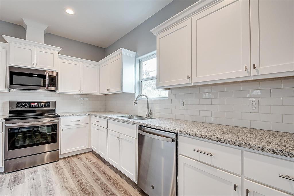 a kitchen with granite countertop white cabinets and stainless steel appliances