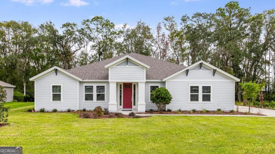 a front view of house with yard and trees in the background