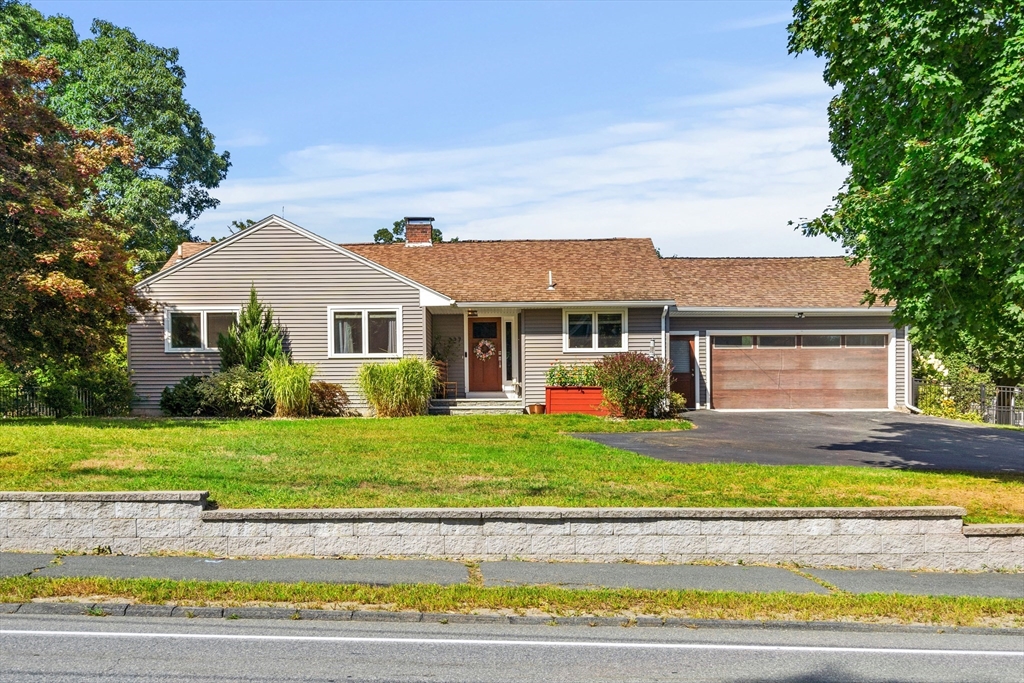 a front view of a house with a yard and potted plants