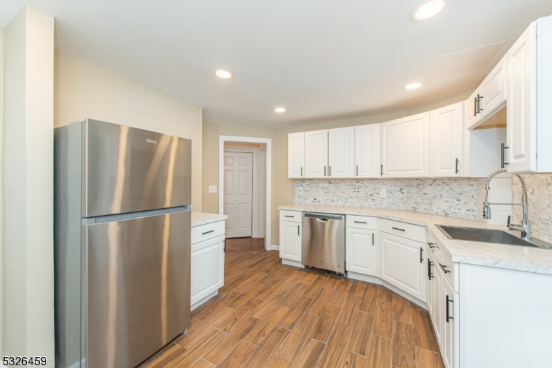 a kitchen with a refrigerator a sink and dishwasher with wooden floor