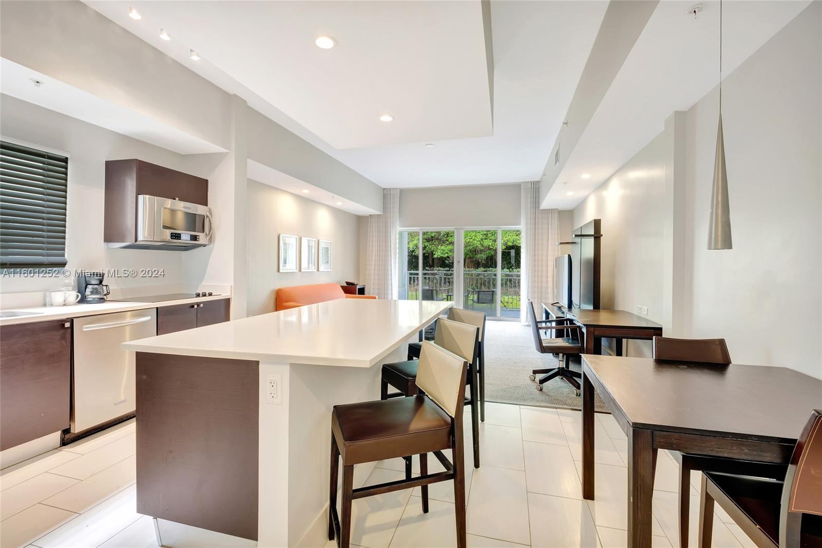 a view of kitchen with stainless steel appliances kitchen island a table chairs in it and wooden floors