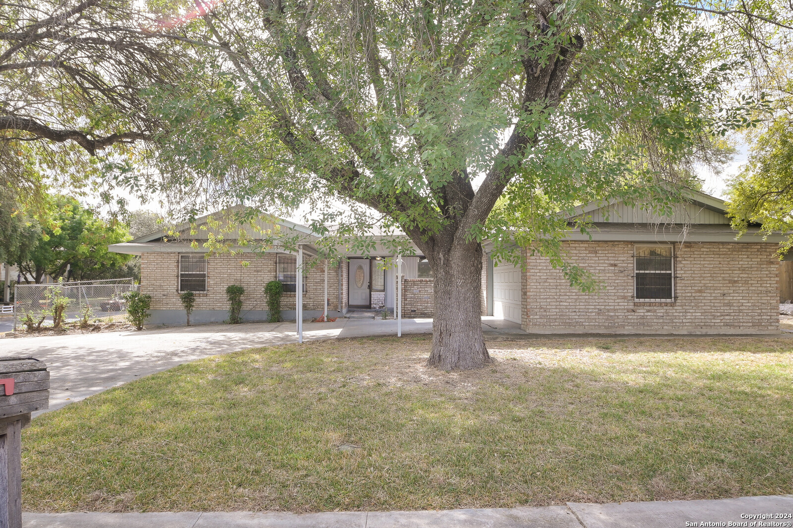 a view of a house with a yard and large tree