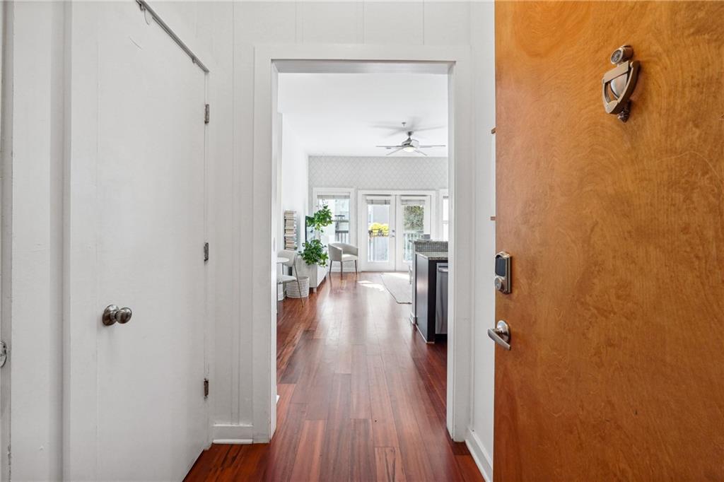 a view of a hallway with wooden floor and a bathroom