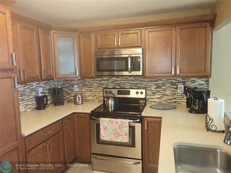 a kitchen with granite countertop a sink stove and microwave