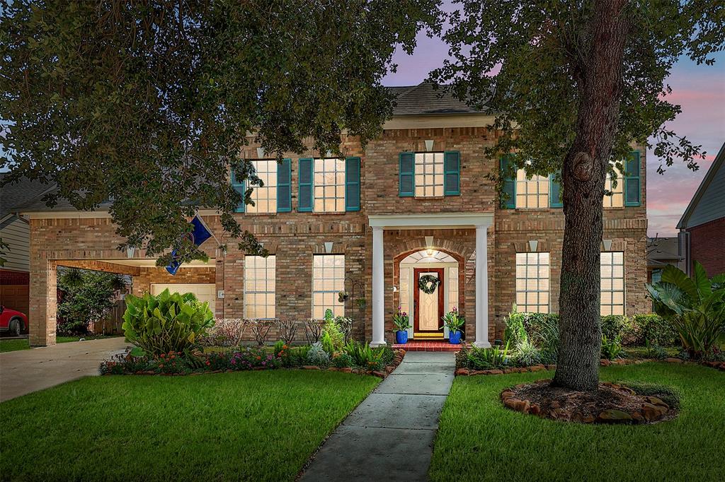 Welcome to 4607 Olive Green Court. This two-story brick home features a well-maintained lawn, mature trees, and an attached two-car garage. This home has a welcoming entrance with a prominent arched doorway.