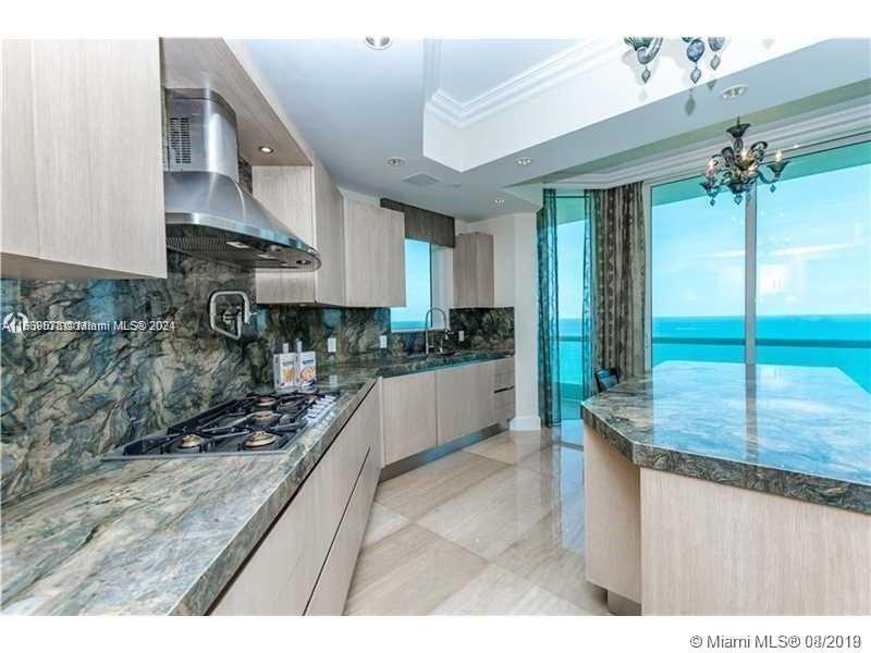 a kitchen with kitchen island granite countertop a sink a counter top space and cabinets