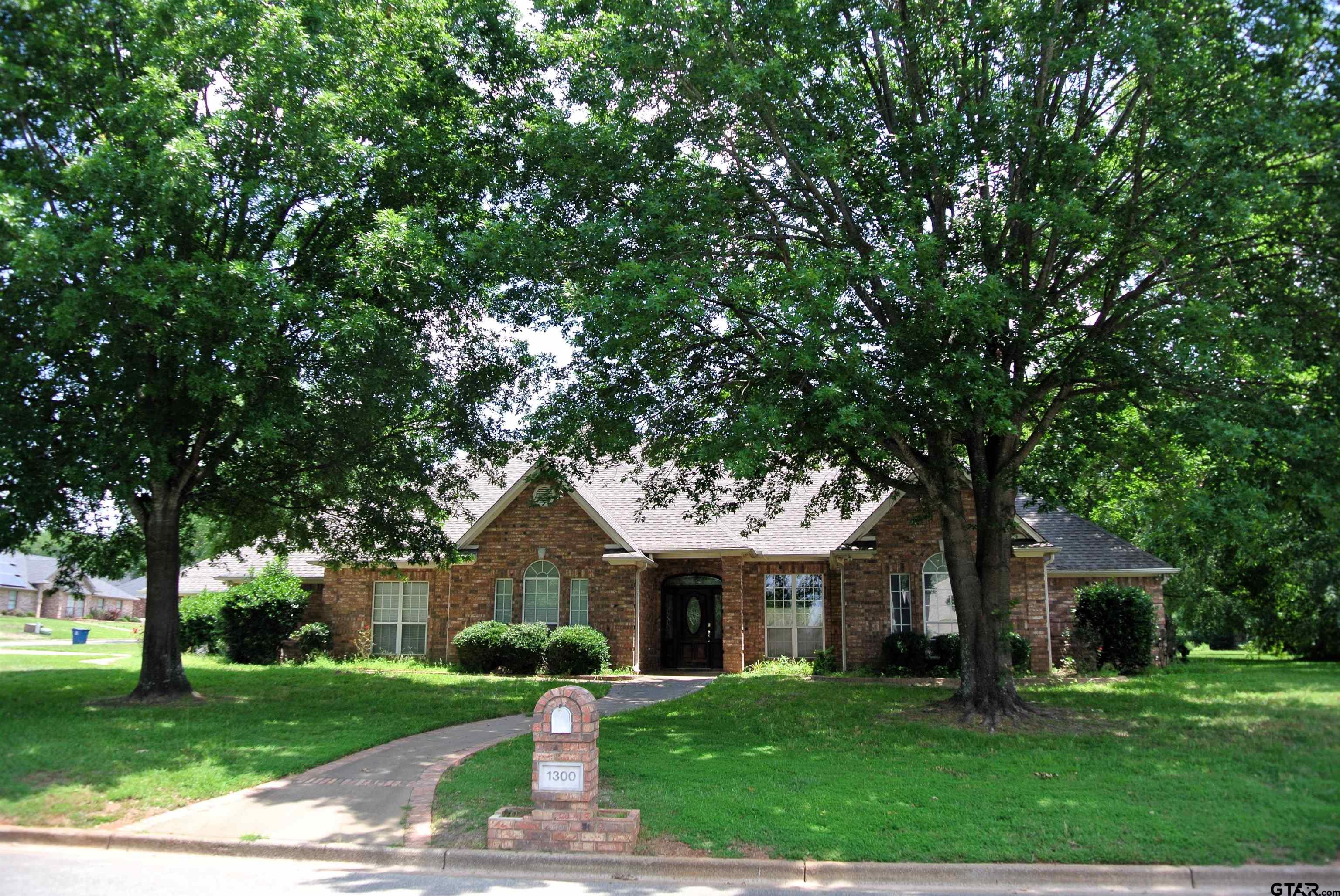 a front view of a house with garden and trees