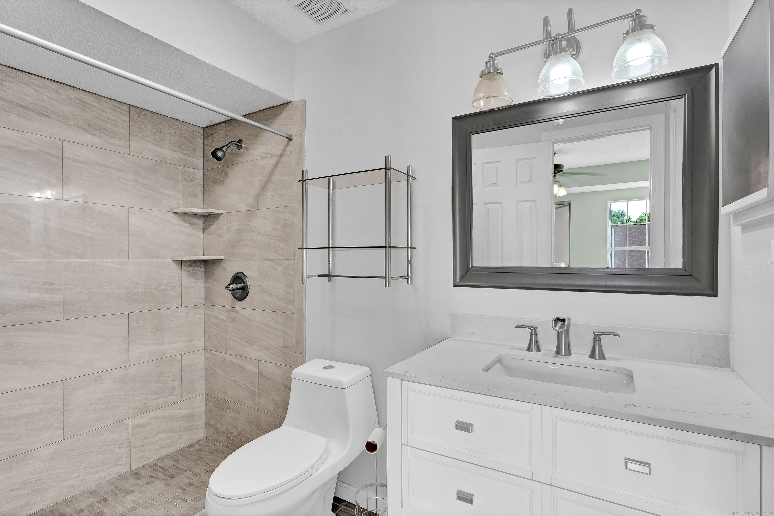 a bathroom with a granite countertop sink toilet a mirror and shower