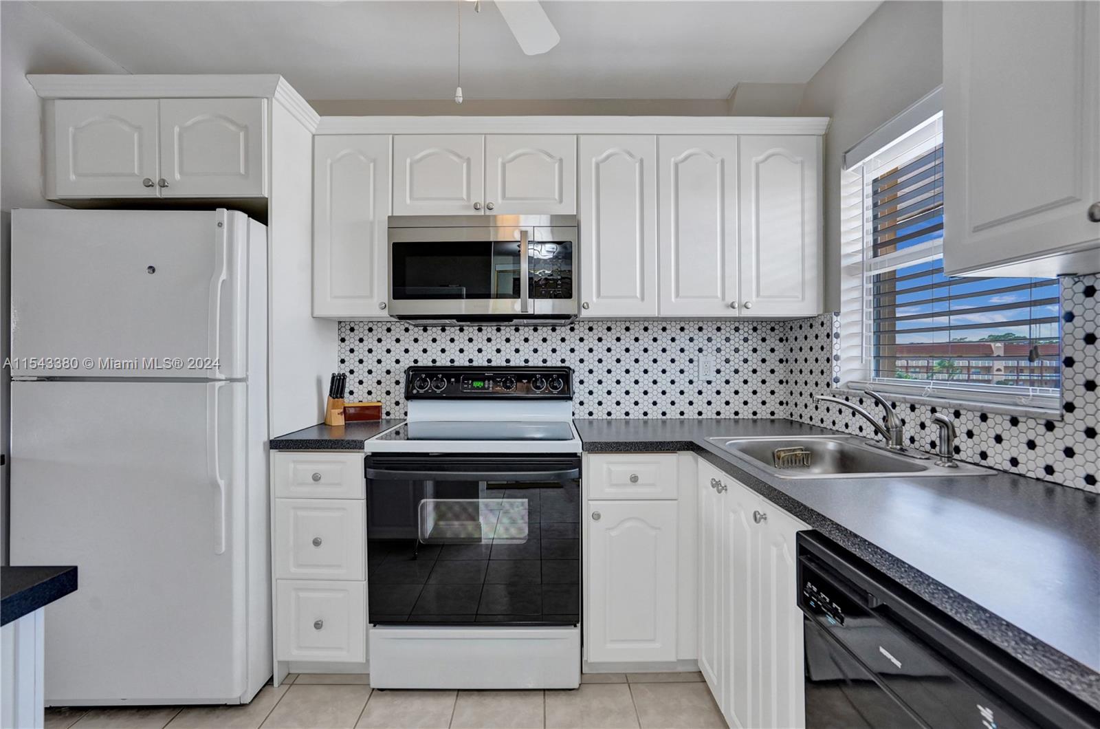 a kitchen with granite countertop a sink stove and refrigerator