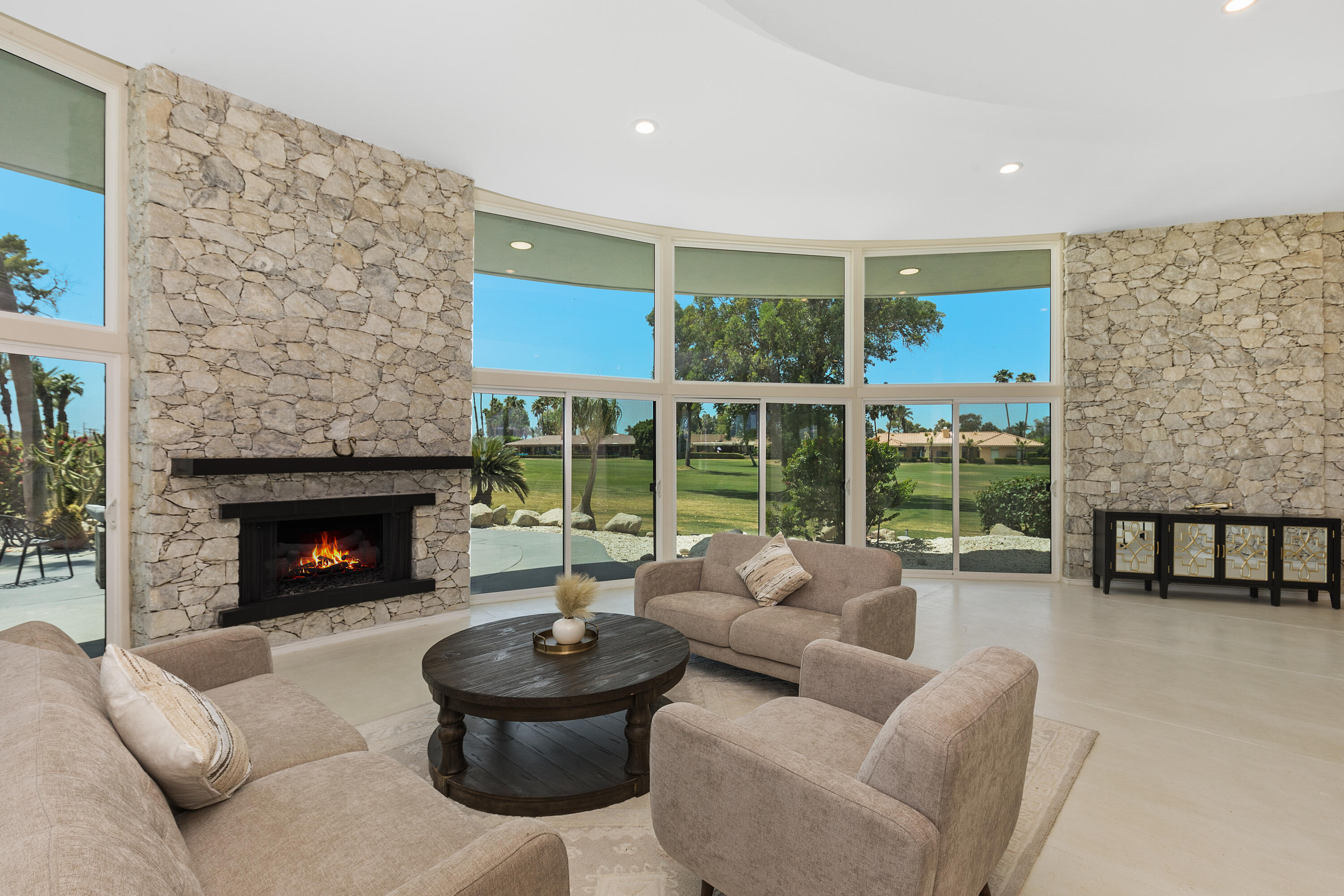 a living room with furniture a fireplace and a floor to ceiling window