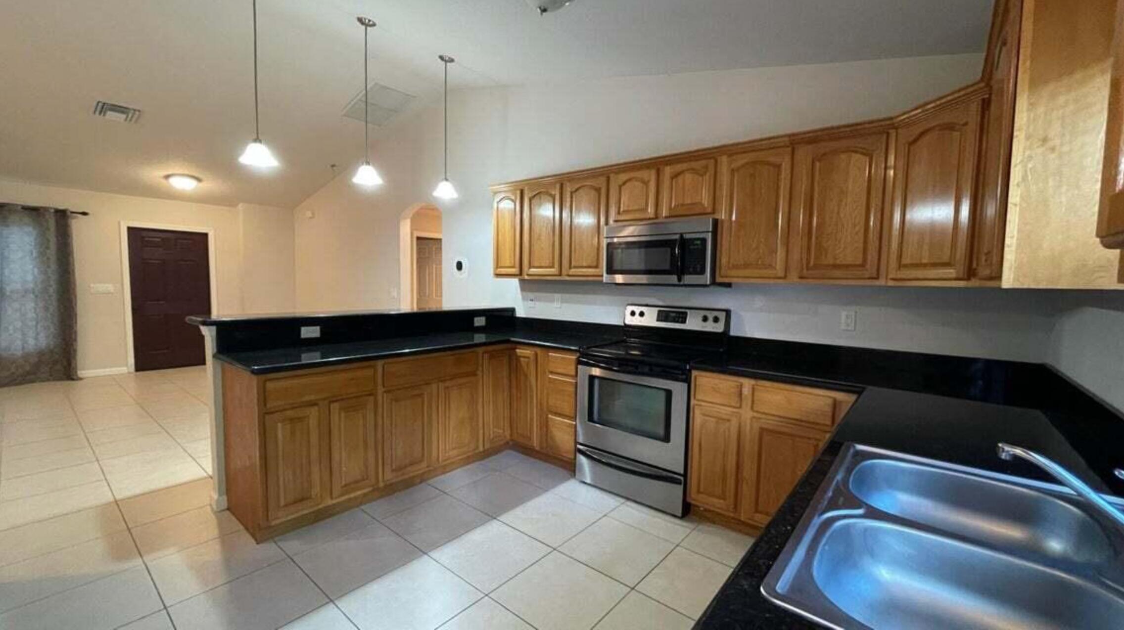 a large kitchen with stainless steel appliances granite countertop a sink a stove counter space and cabinets