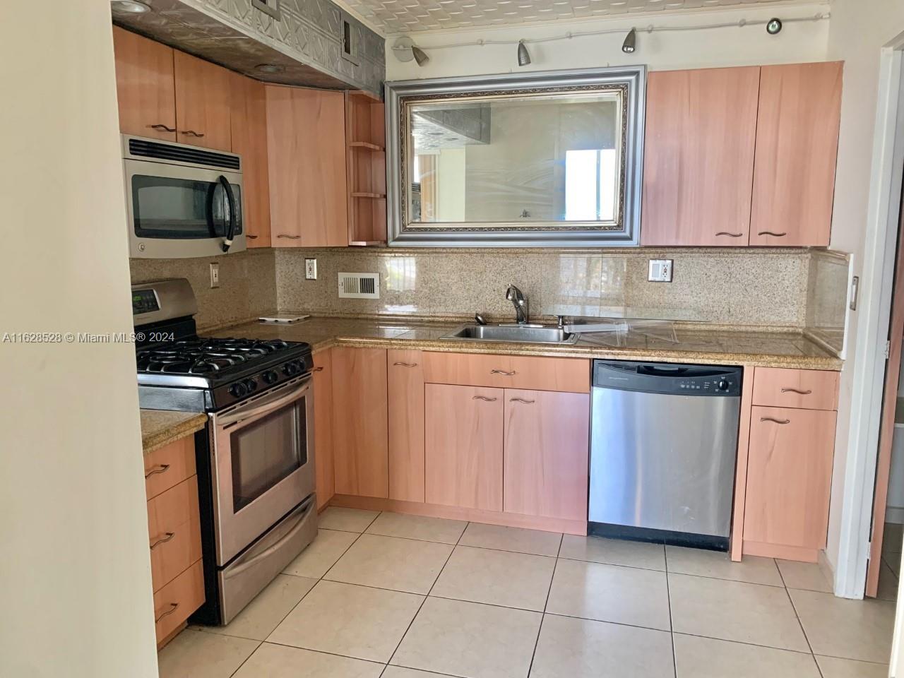 a kitchen with granite countertop a stove top oven microwave and cabinets