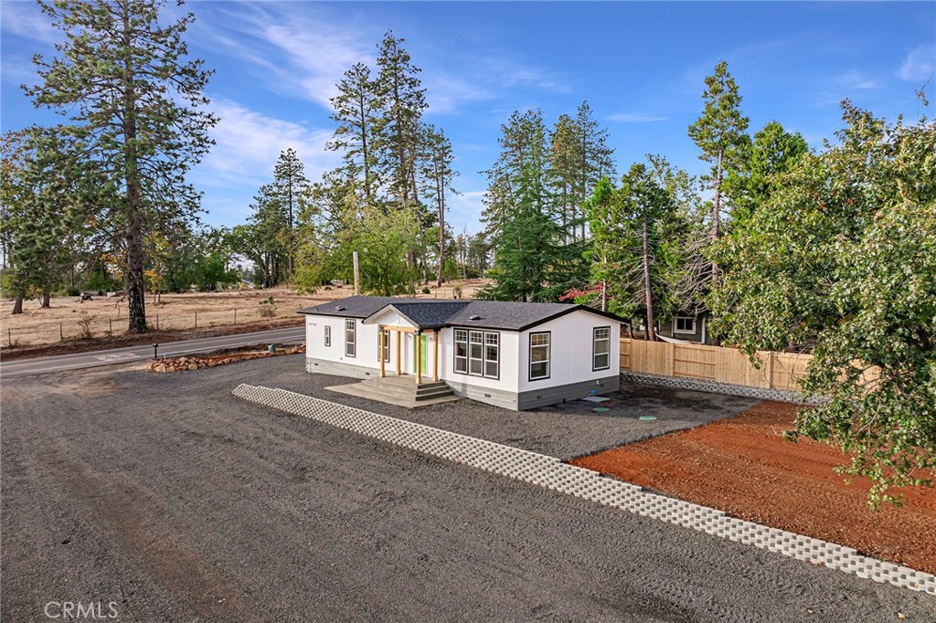 a view of a house with a yard and large trees