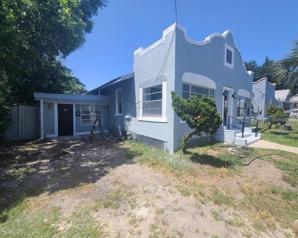 a view of a house with a yard and large tree