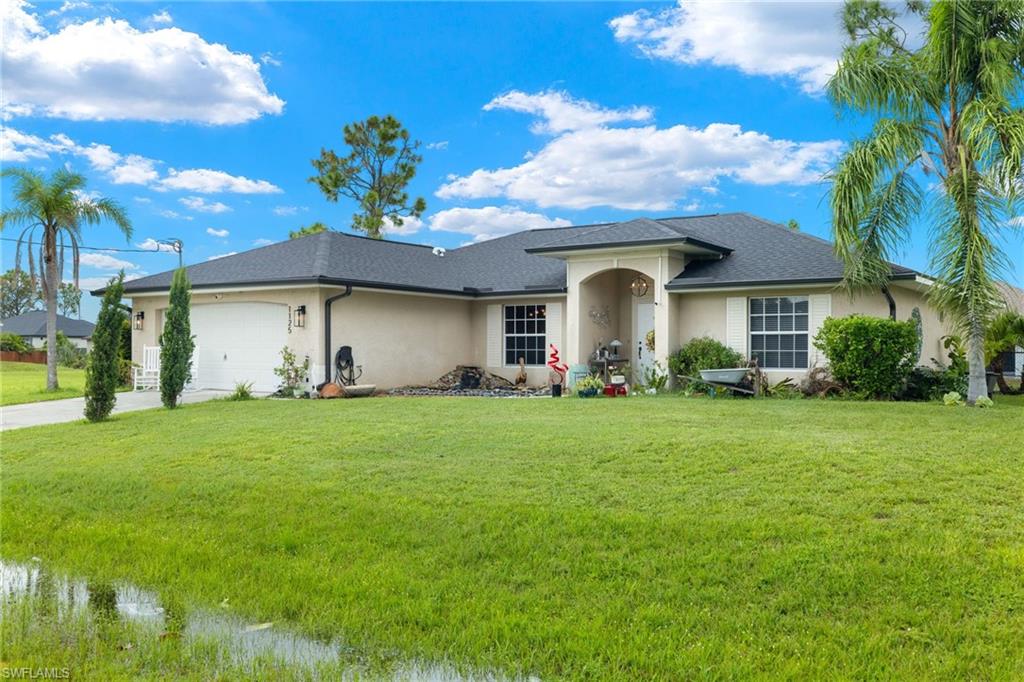 View of front facade featuring a garage and a front lawn